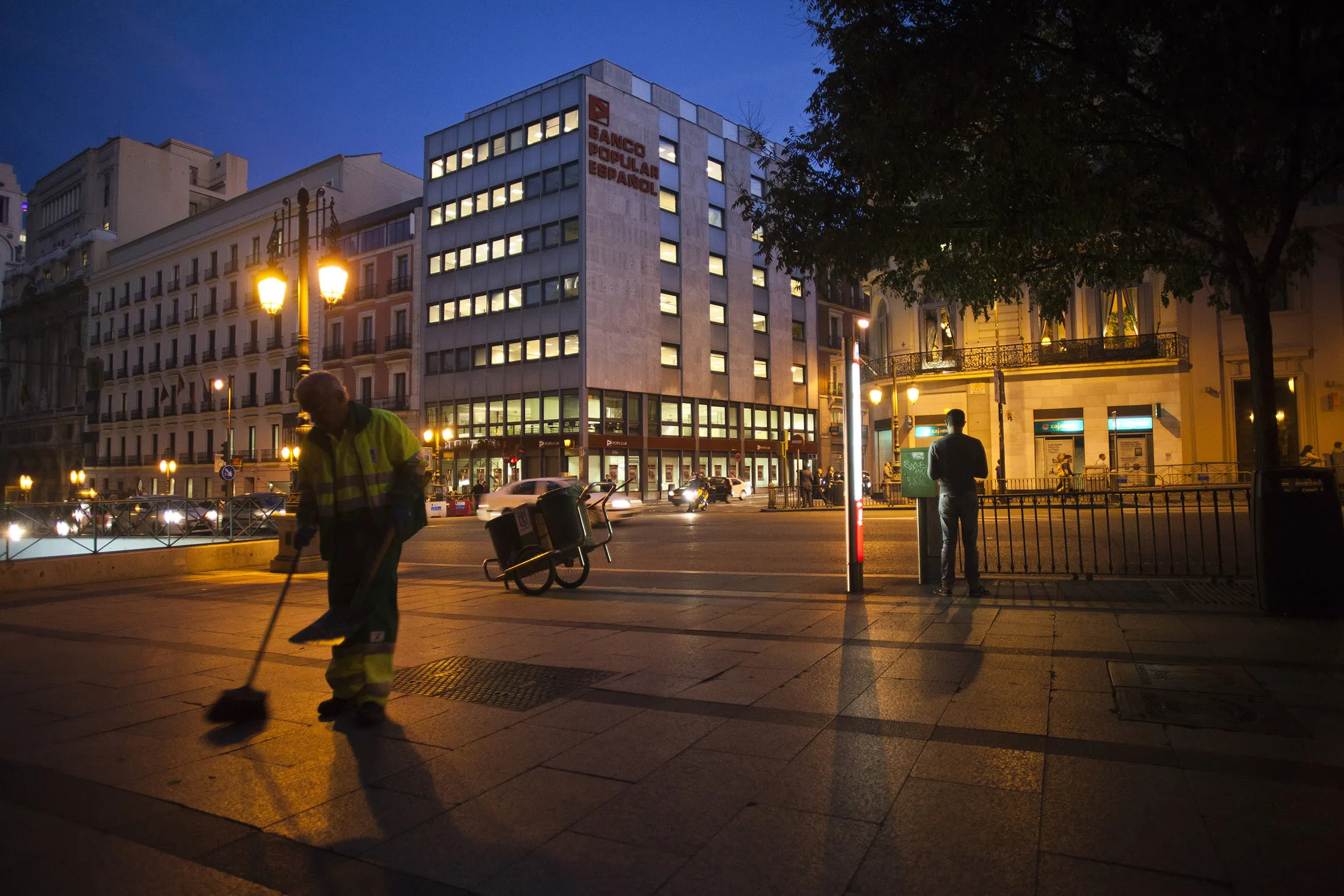 A street cleaner works by the headquarters of Banco Popular Espanol SA in Madrid, Spain, on Tuesday, Oct. 2, 2012. Banco Popular Espanol SA is defying the findings of Spain's bank stress tests as it seeks new money from Allianz SE and other investors to plug a capital shortfall.
