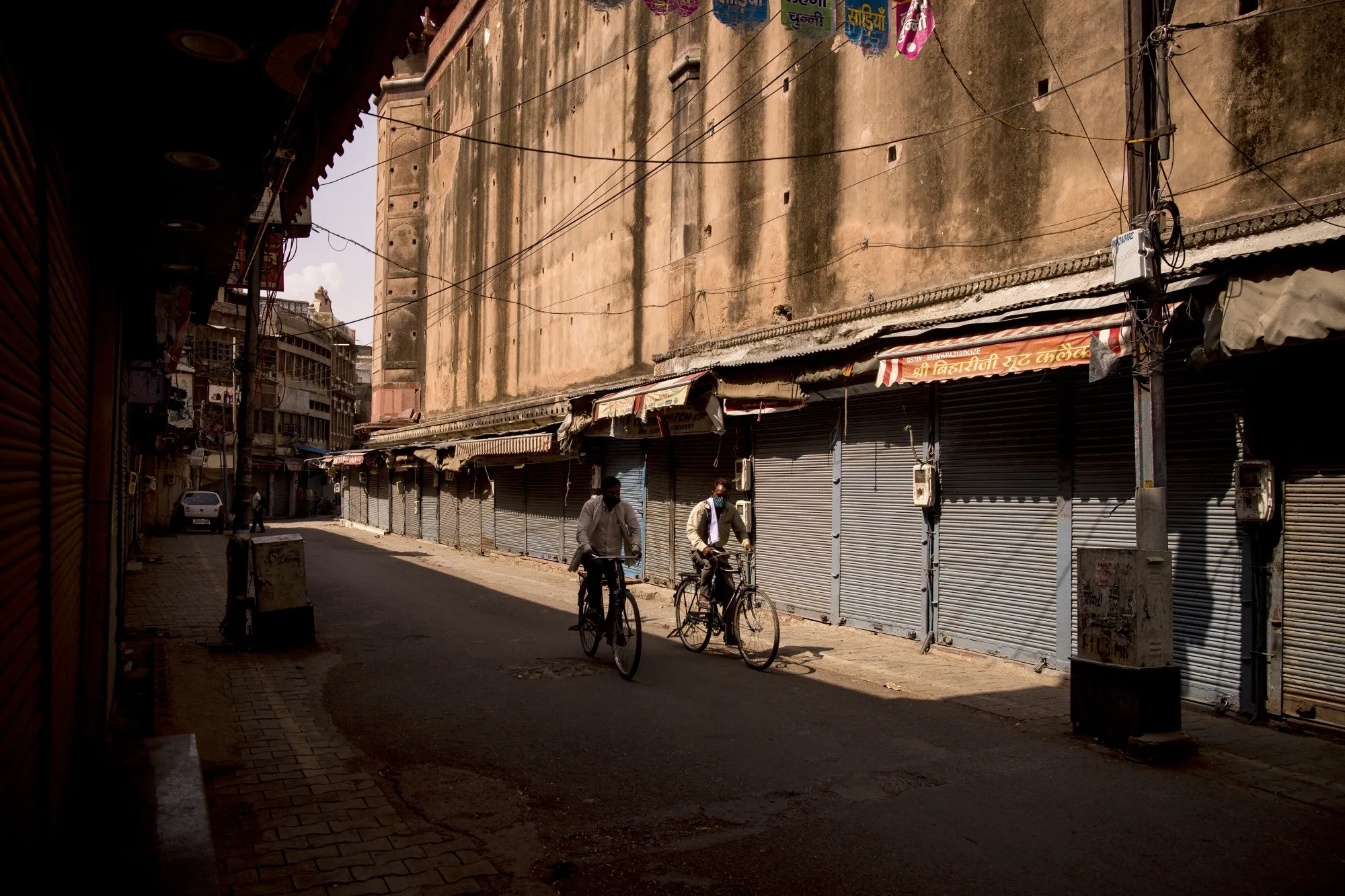 Cyclists ride past closed stores in a deserted market area&nbsp;in Agra, Uttar Pradesh, India.