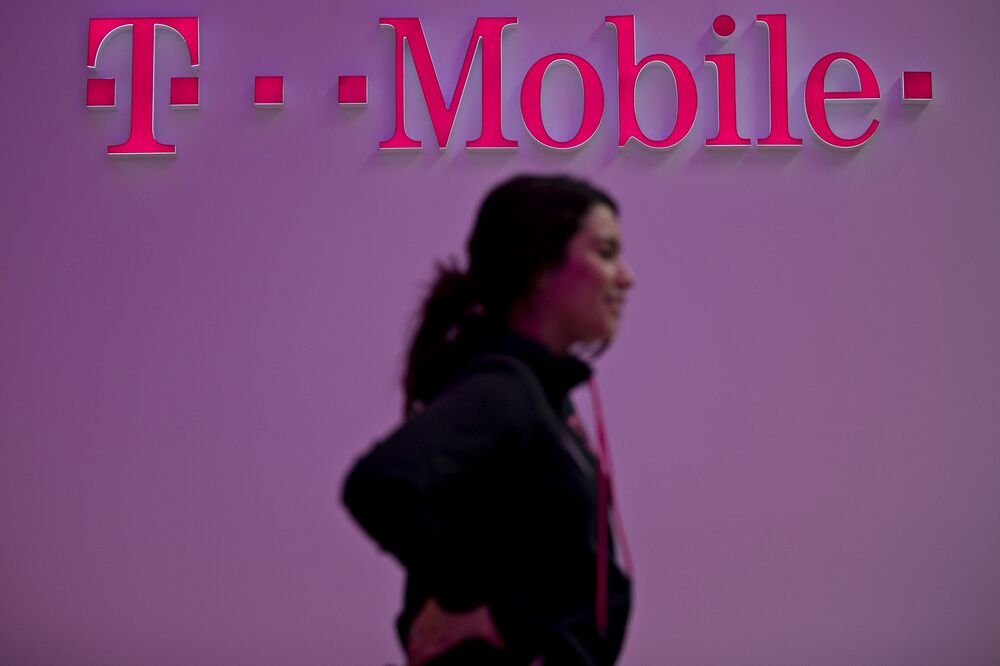 An employee stands near signage at a T-Mobile US Inc. store in Chicago, Illinois, U.S.