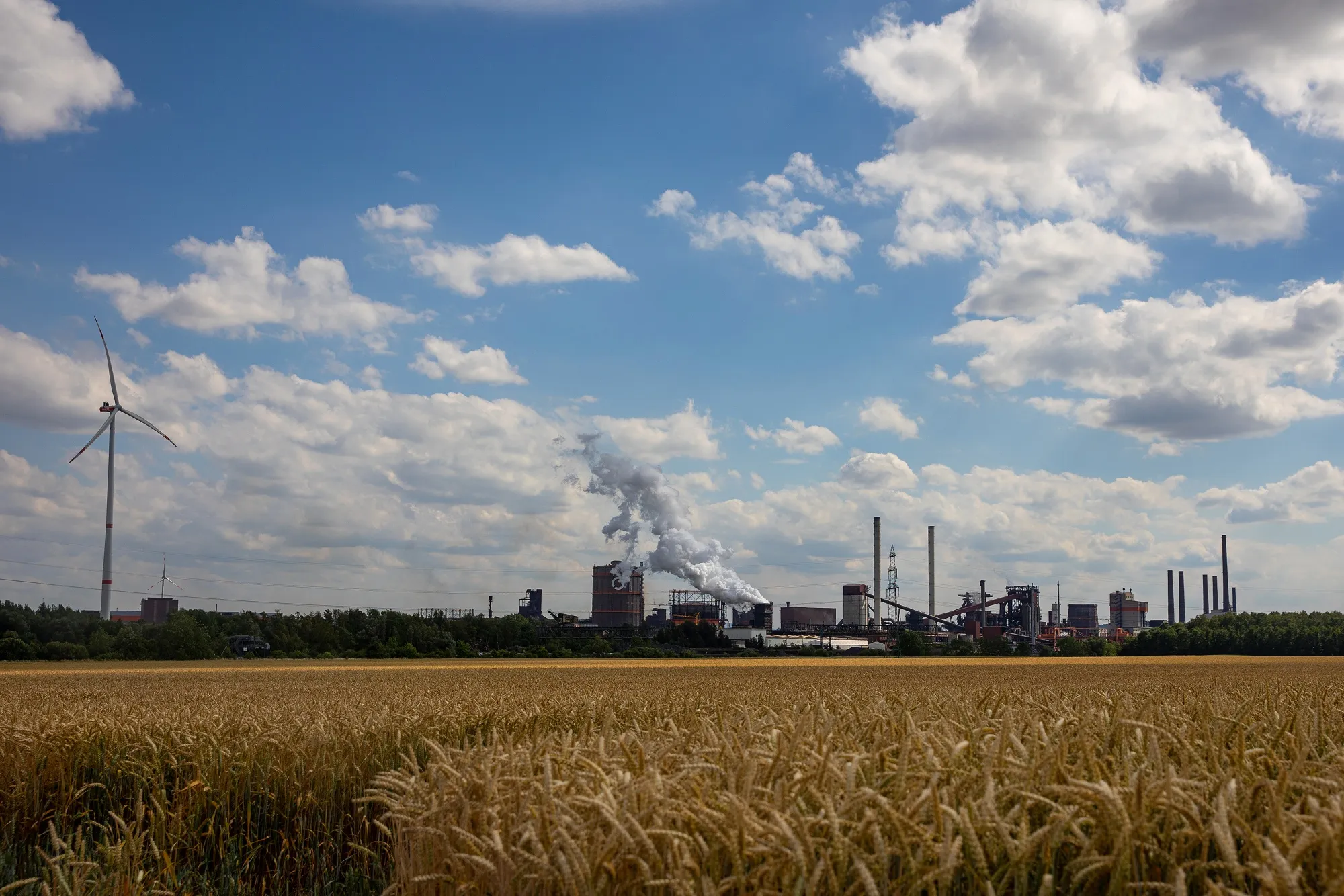 Wind turbines operated by Salzgitter AG, part of the Salzgitter Low CO2 Steelmaking (SALCOS) green steel project, and vapor rising from the coke quenching tower at the company's mill in Salzgitter, Germany, in 2022.