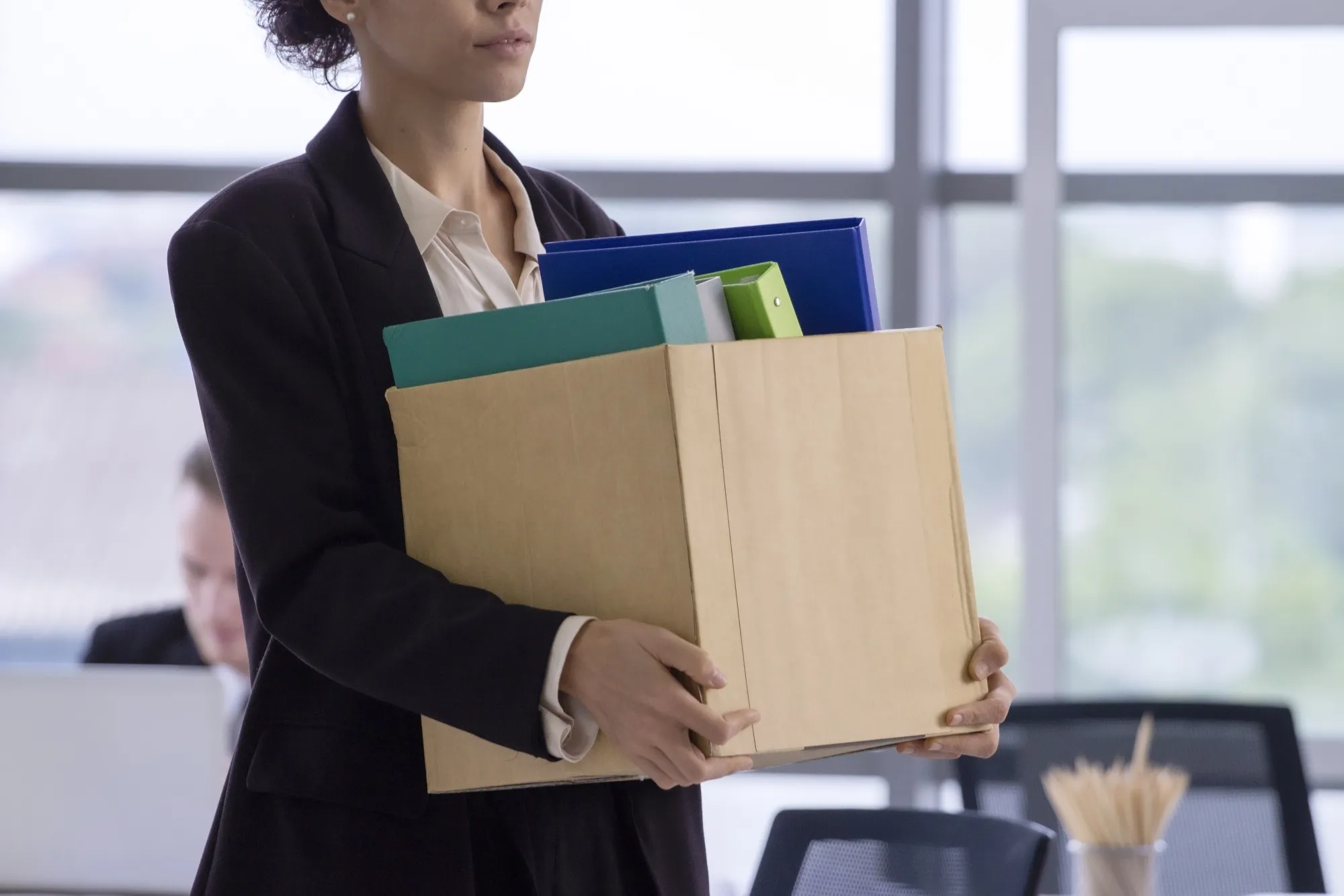 Business concept : An unemployed with her cardboard box walking out of the office