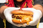Slutty Vegan founder Pinky Cole holds a burger dripping with the infamous slut sauce.