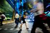 Commuters cross a road at night in the central business district of Singapore.