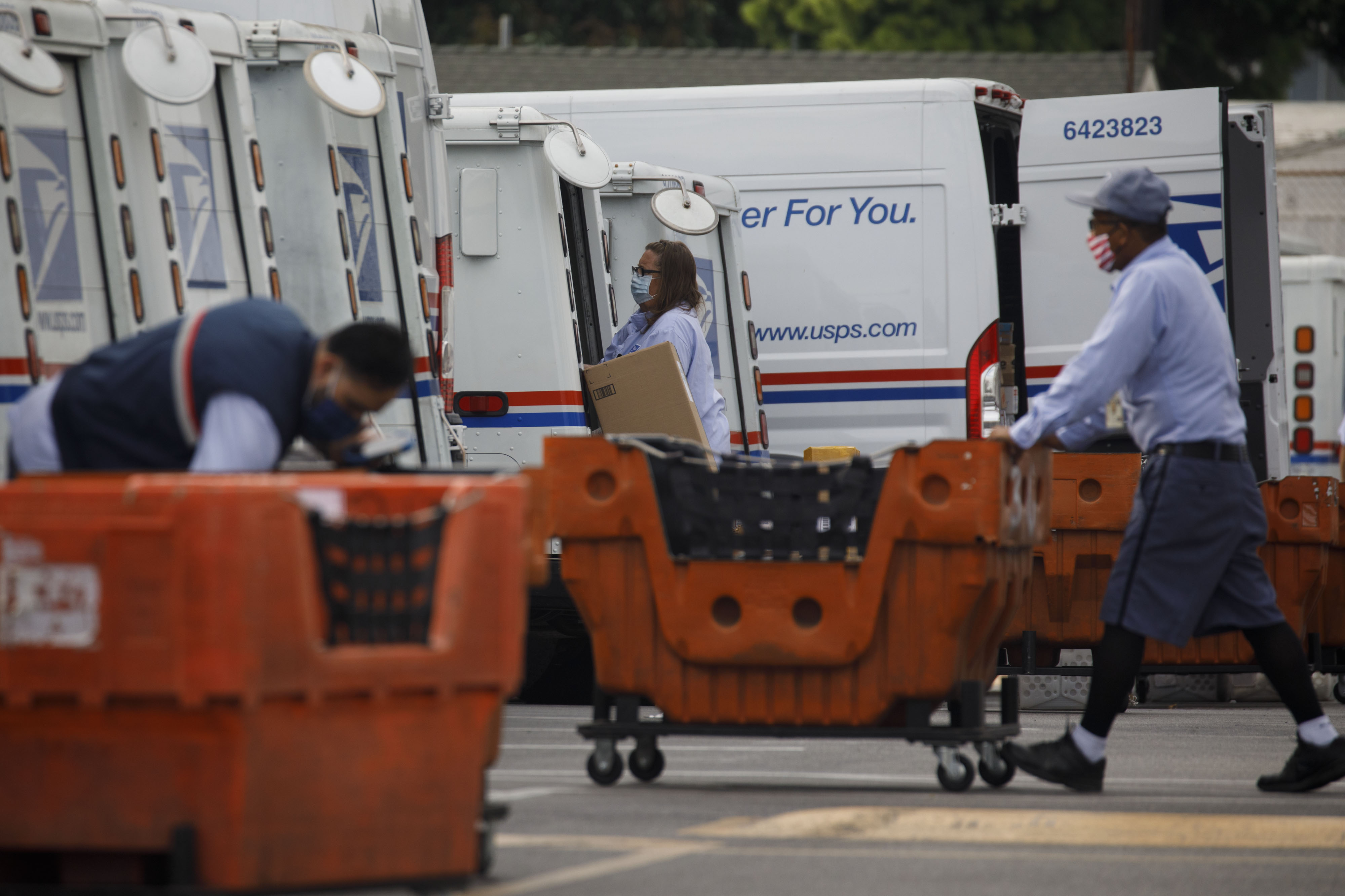 U.S. Postal Service employees load mail and packages into delivery vehicles outside a post office in Torrance, California, on Aug. 17.