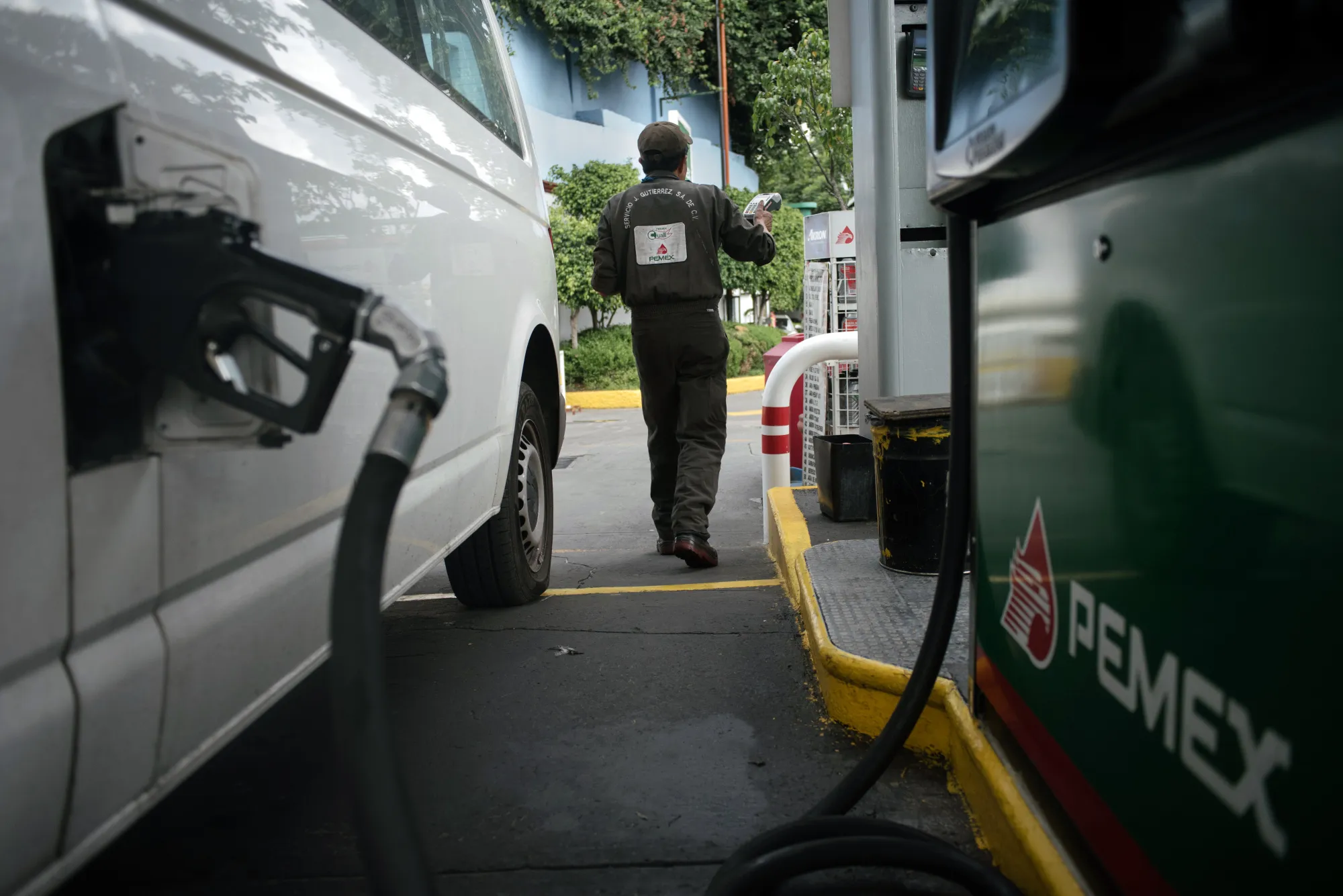 An attendant walks past a vehicle being fueled at a Petroleos Mexicanos (Pemex) gas station in Mexico City, Mexico.