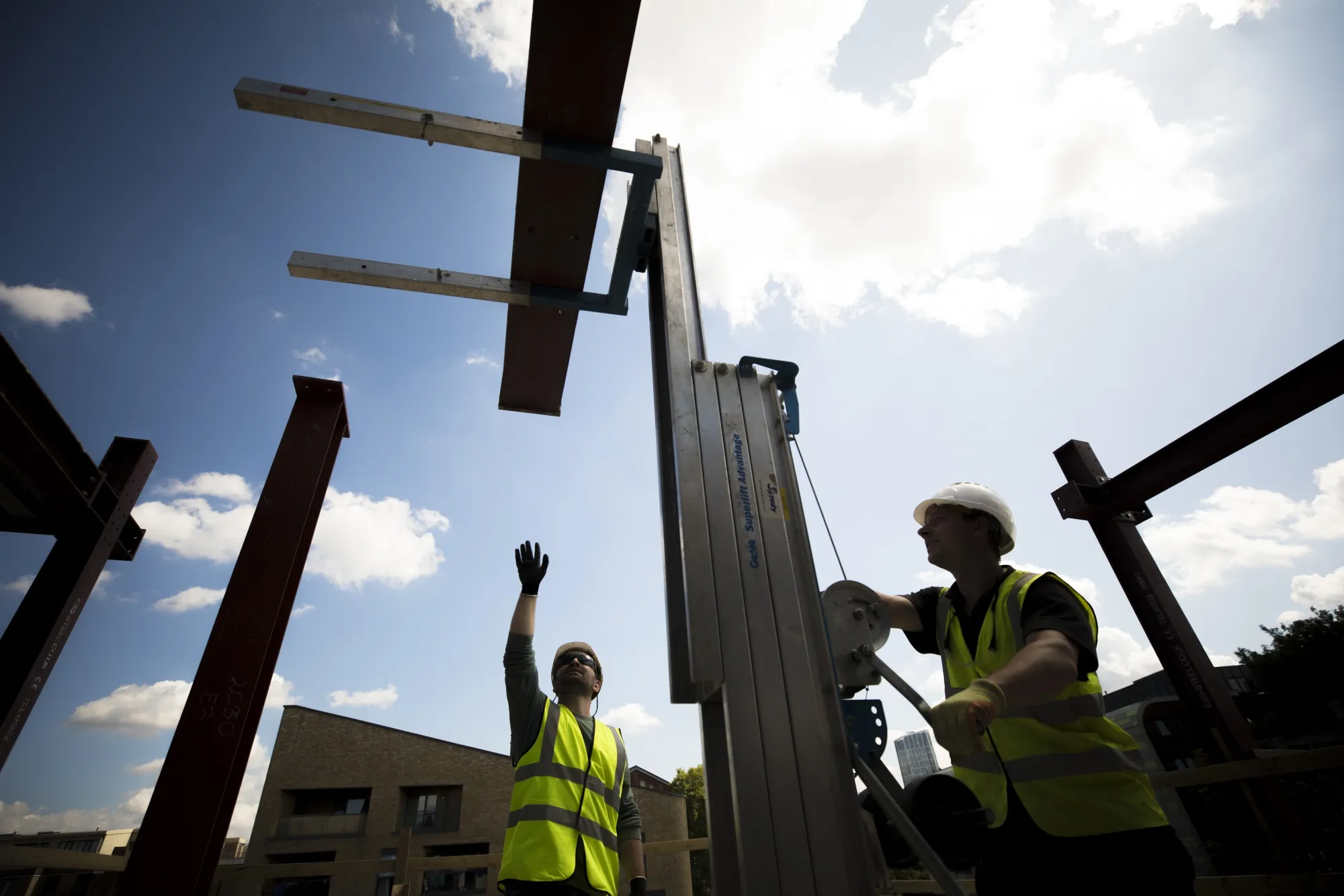 Construction workers lift a steel beam on a residential site in London.