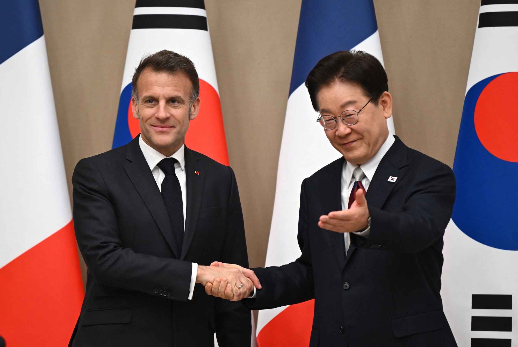 Emmanuel Macron, left, shakes hands with Lee Jae Myung in Seoul on April 3.