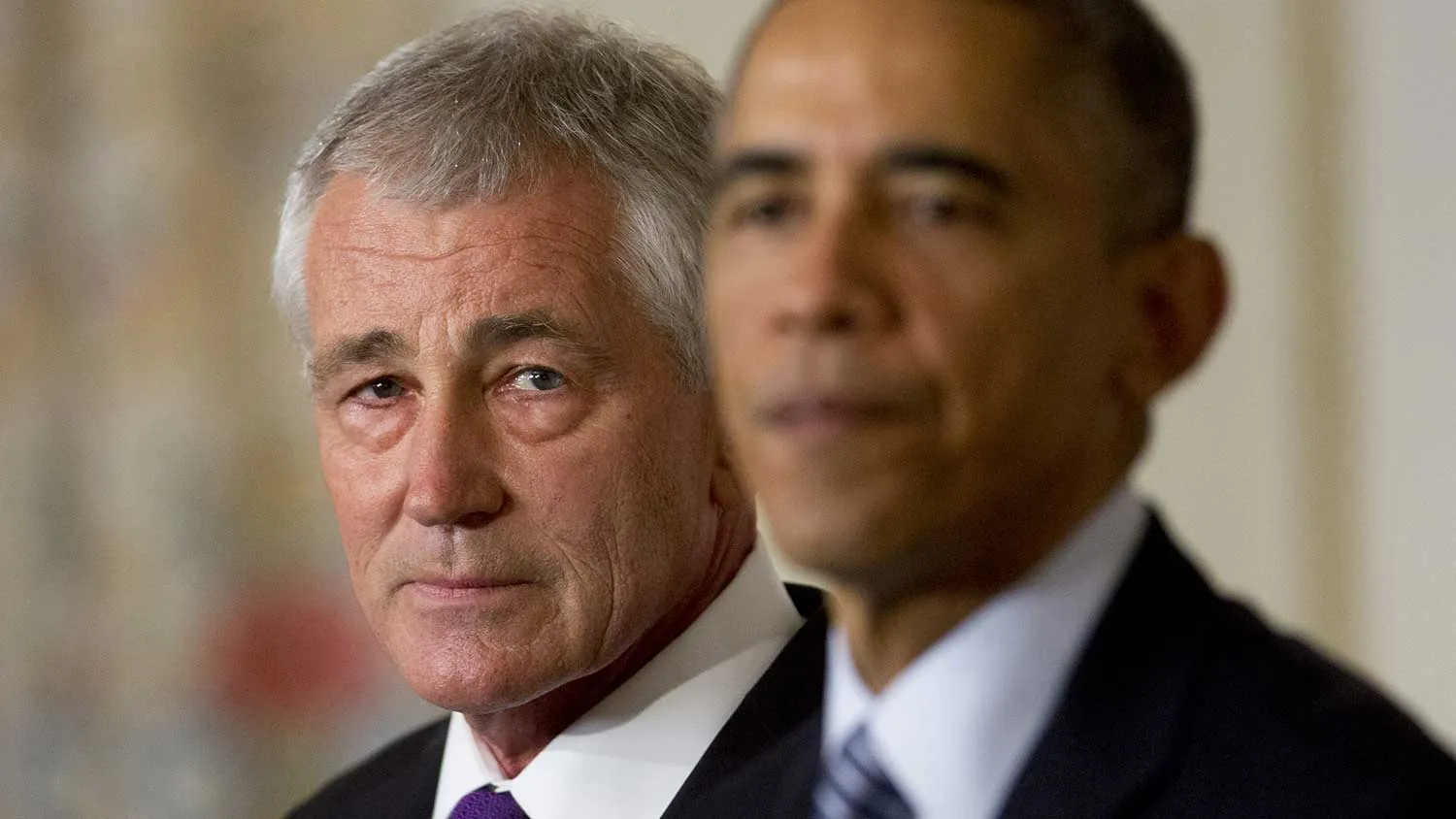 Chuck Hagel, U.S. secretary of defense, left, listens as U.S. President Barack Obama speaks in the State Dining Room of the White House in Washington, D.C., U.S., on Monday, Nov. 24, 2014.
