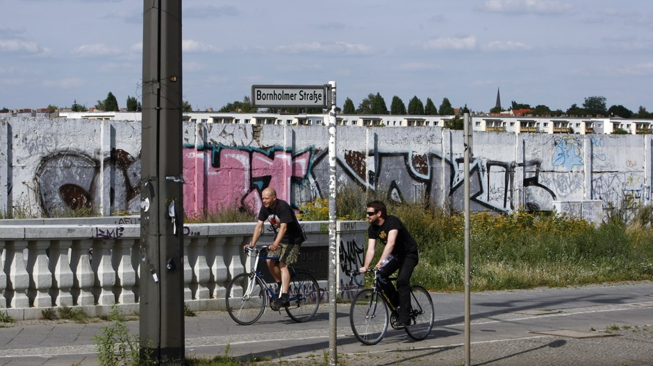 Cyclists using one of Berlin's old-style sidewalk bike lanes near a remaining section of the Berlin Wall