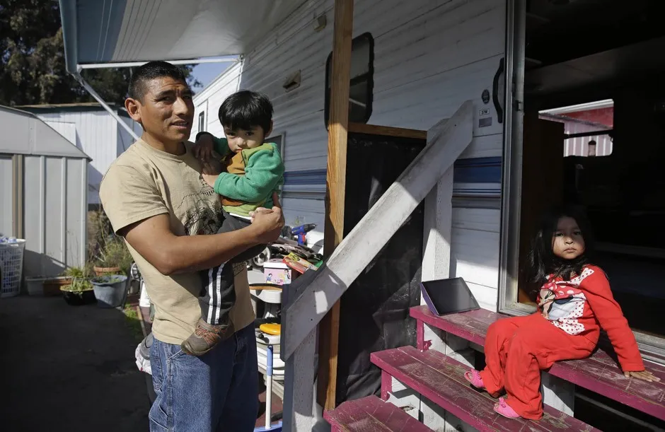 Alex Simangas, a cook at a local pizza restaurant, stands with his son Alex and daughter Teresa outside their home at the Buena Vista Mobile Home Park, Tuesday, Feb. 3, 2015, in Palo Alto, California.