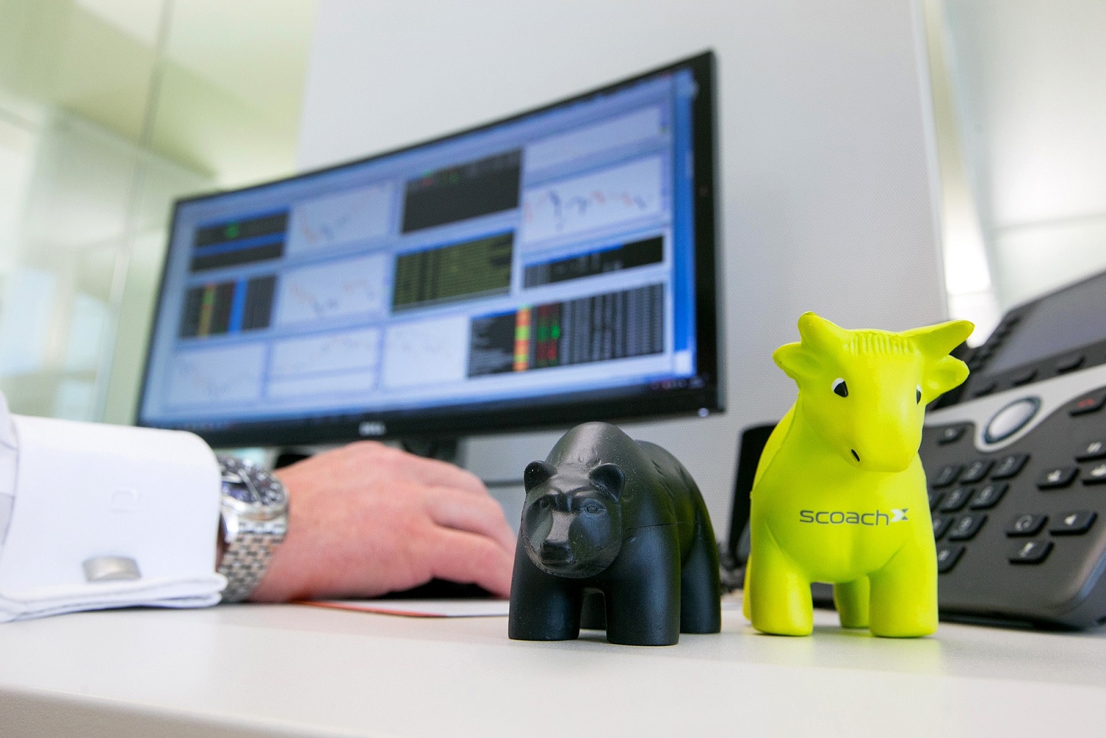 An employee monitors financial data as toy bear and bull figurines sit on a desk inside FinTech Group AG's campus offices.
