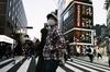 Pedestrians wearing protective masks cross a road in the Shinjuku district of Tokyo, Japan.