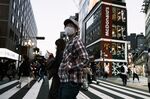 Pedestrians wearing protective masks cross a road in the Shinjuku district of Tokyo, Japan.