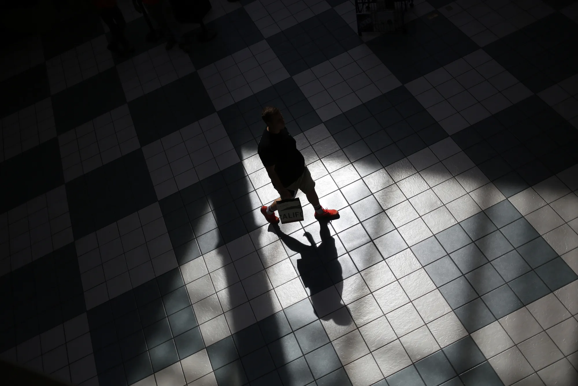 The shadow of a pedestrian carrying a shopping bag is seen on the floor tiles of the Easton Town Center shopping mall in Columbus, Ohio, U.S., on Tuesday, Aug. 23, 2016. The Conference Board is scheduled to release consumer confidence data on Aug. 30.