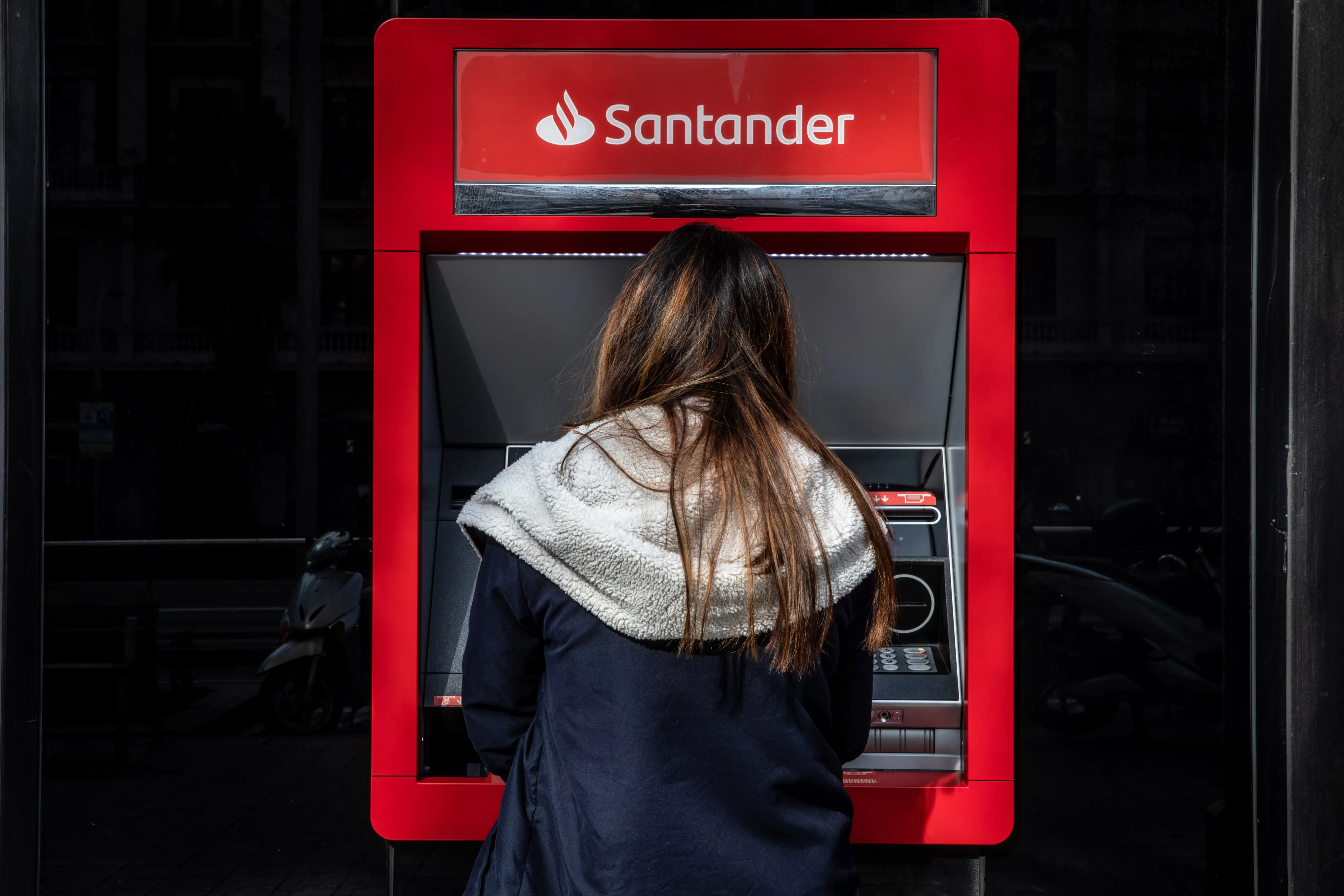A customer uses an ATM outside a Banco Santander SA bank branch in Barcelona.