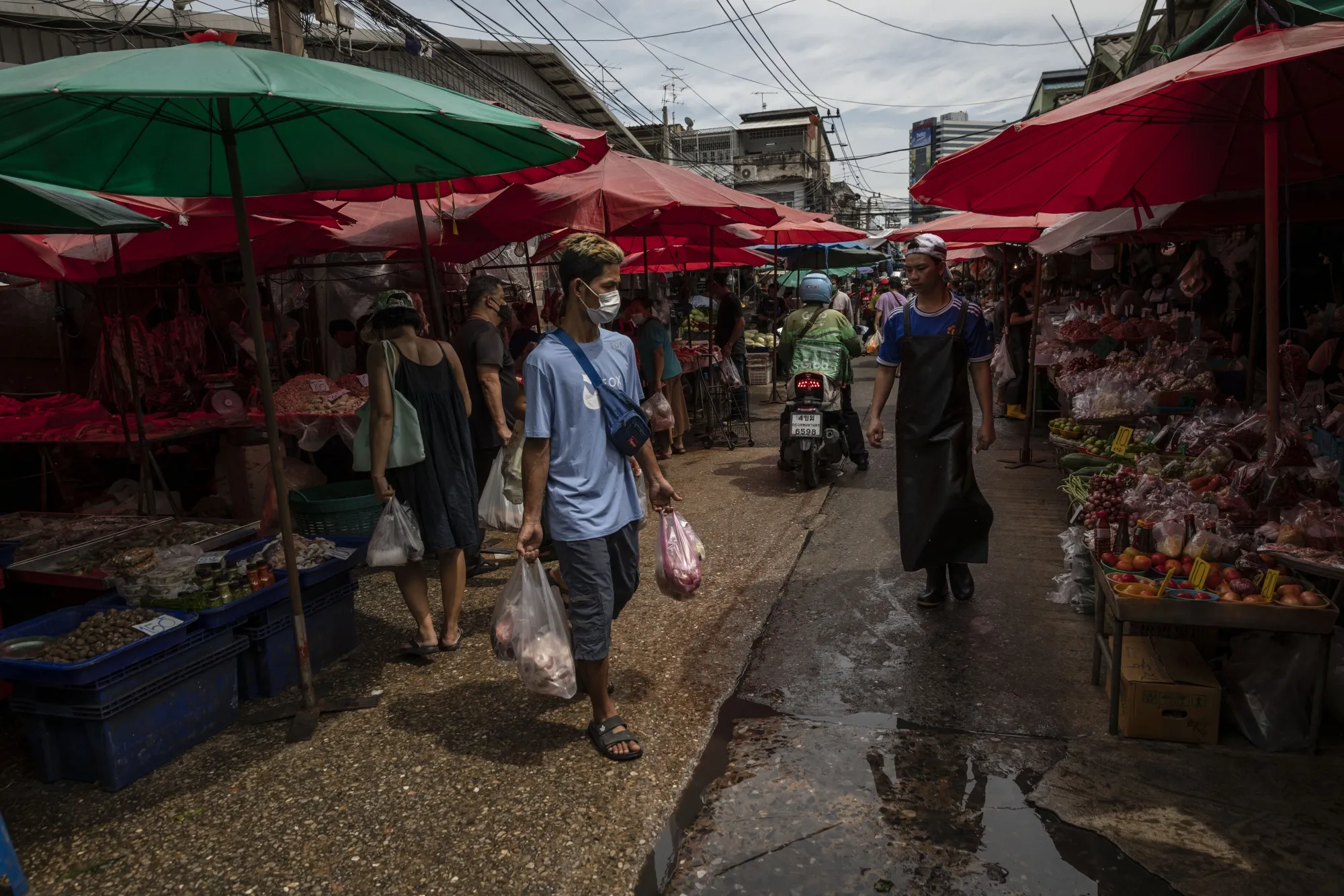 A man carries groceries through a wet market in Bangkok, earlier in July.