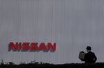A pedestrian walks past signage for Nissan Motor Co. outside the company's headquarters in Yokohama, Japan, on Tuesday, March 12, 2019. 