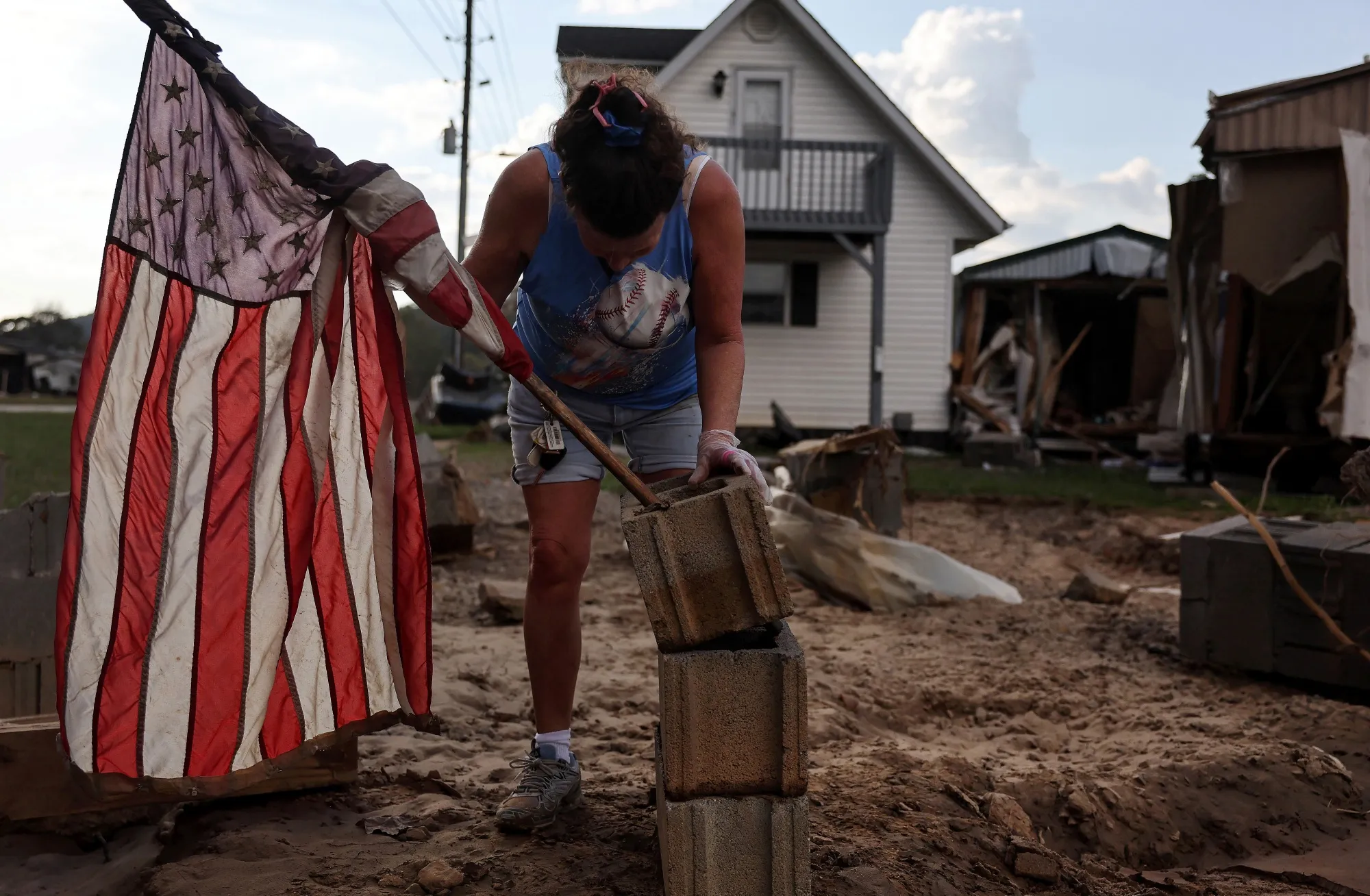 A woman mounts a flag to a stack of cinderblocks in the aftermath of flooding from Hurricane Helene&nbsp;in Swannanoa, North Carolina,&nbsp;on Oct.&nbsp;6, 2024.&nbsp;