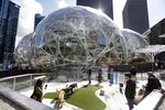 Amazon employees tend to their dogs as construction continues on three large, glass-covered domes as part of an expansion of the company's campus in downtown Seattle. 