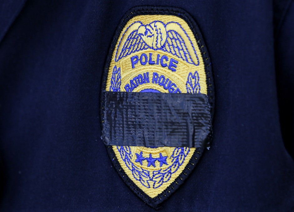 A Baton Rouge police officer wears a mourning band of black tape on his uniform near a memorial for three police officers shot and killed in the city on Sunday.
