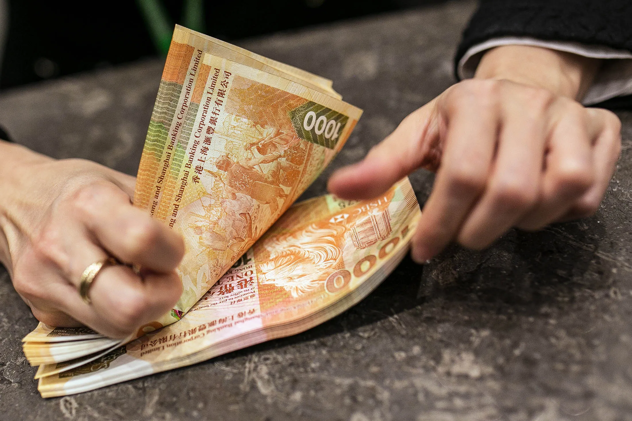 An employee counts Hong Kong one thousand dollar banknotes in this arranged photograph inside the Hang Seng Bank Ltd. headquarters in Hong Kong, China, on Wednesday, Feb. 18, 2015. Hang Seng Bank, majority-owned by HSBC Holdings Plc, is scheduled to announce full-year earnings on Feb. 23.
