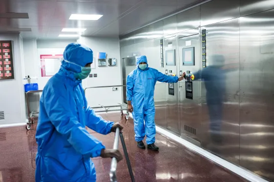 Technicians monitor a sterilizing machine in a sterilization unit at a pharmaceutical plant.