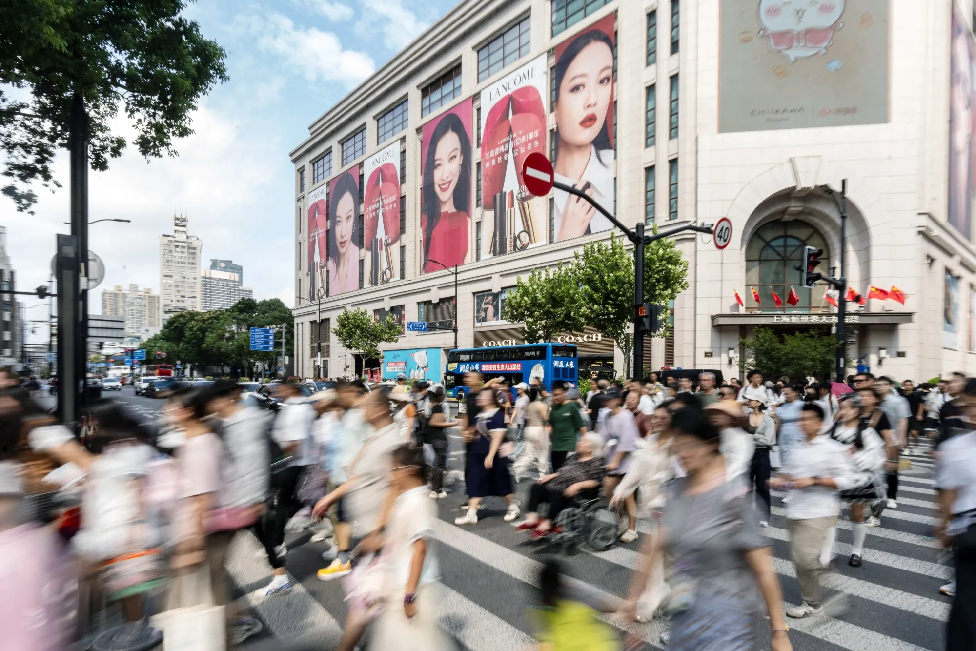 Pedestrians cross a road in the Nanjing Road shopping area during the Golden Week holiday in Shanghai, China, on Thursday, Oct. 2, 2025.