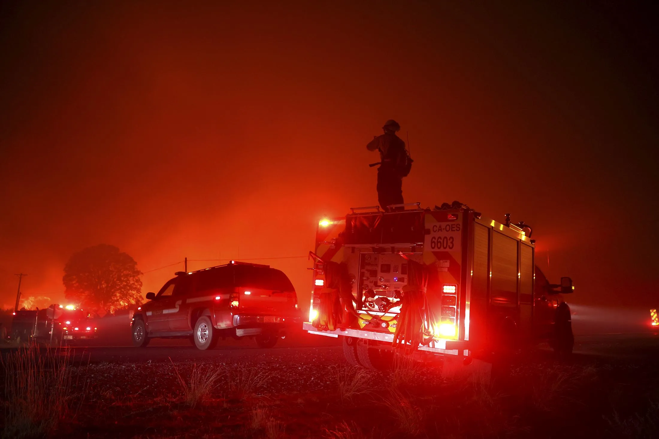 A firefighter monitors the Dixie Fire as it burns along Highway 395 near Janesville, California, on Aug. 16.