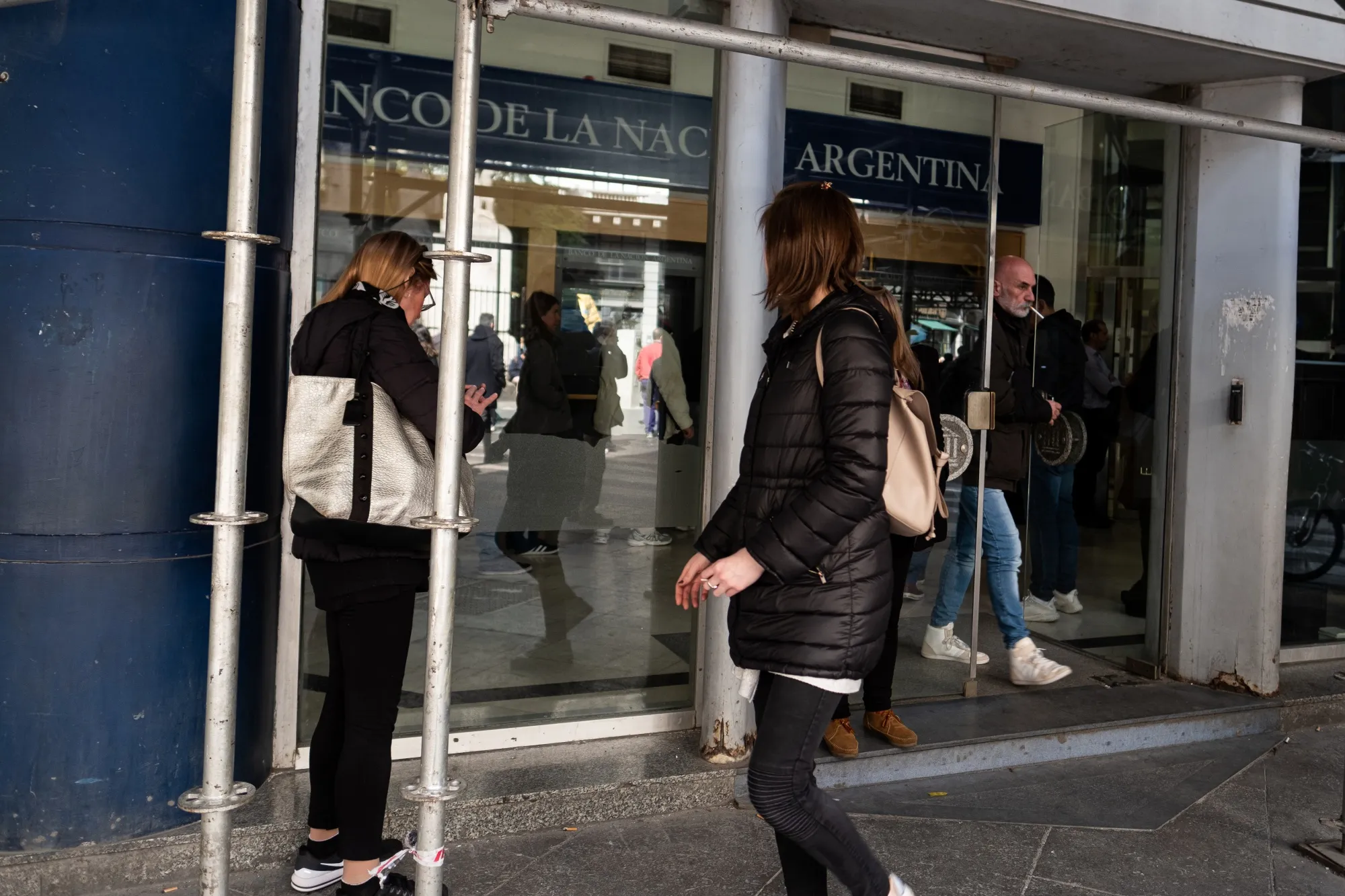 Pedestrians walk past a Banco de la Nacion Argentina branch in Buenos Aires, Argentina.