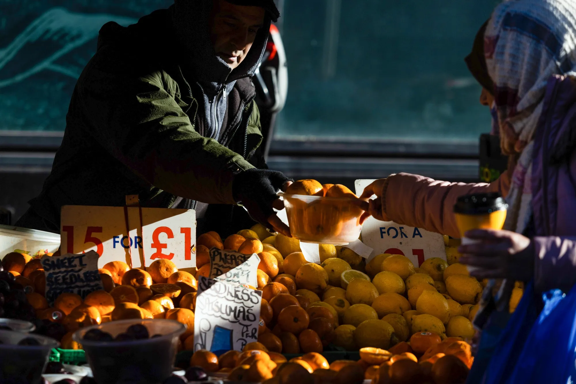 A stall holder serves a customer&nbsp;at a market stall in Croydon, U.K.