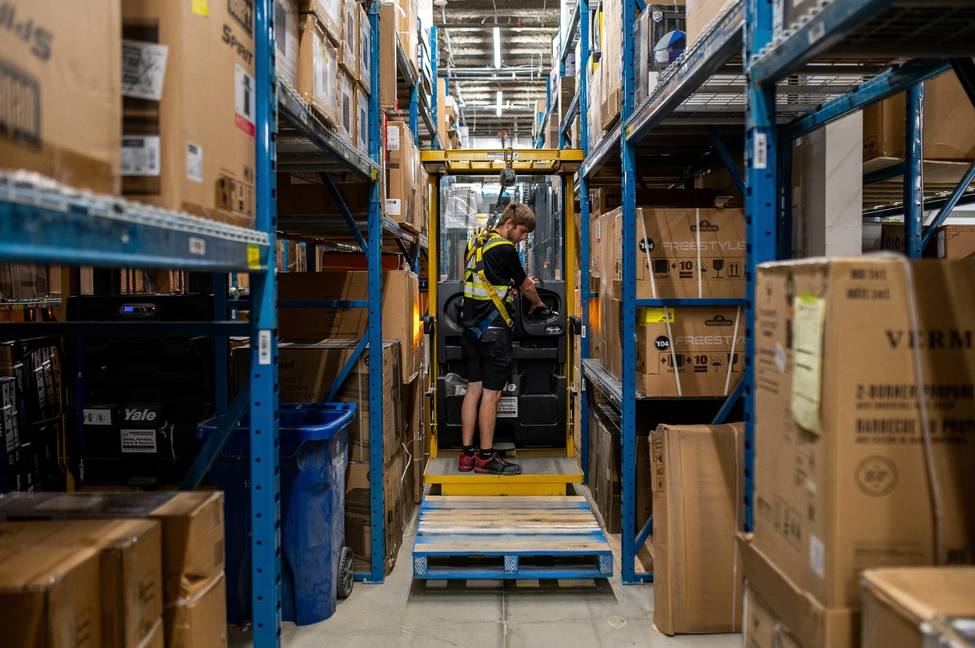 A worker picks products with a lift in the warehouse of a Hillside Canadian Tire store in Victoria, British Columbia.