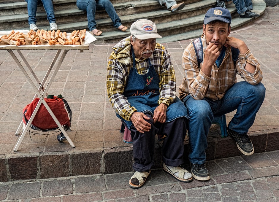 A vendor selling sweet pastries sits with his friend near a church in Guanajuato, Mexico.