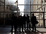 Commuters stand silhouetted against the window as they wait for a Docklands Light Railway (DLR) train.