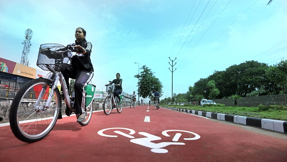 Young women riding public bikes on a designated bike lane in Bhopal.
