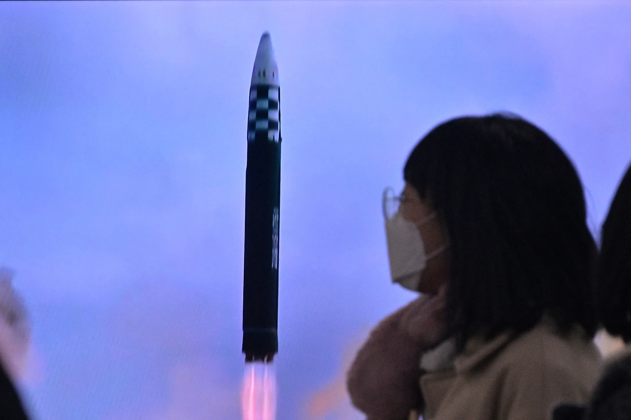 A woman walks past a television showing a news broadcast with file footage of a North Korean missile test, at a railway station in Seoul on Feb.&nbsp;18.