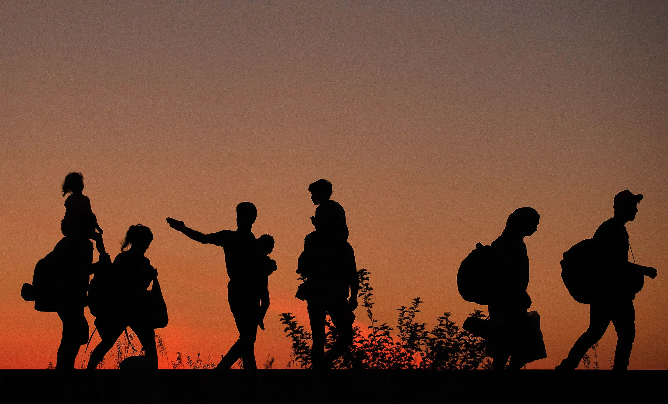Migrants walk along a railway line after they have crossed the border from Serbia into Hungary.
