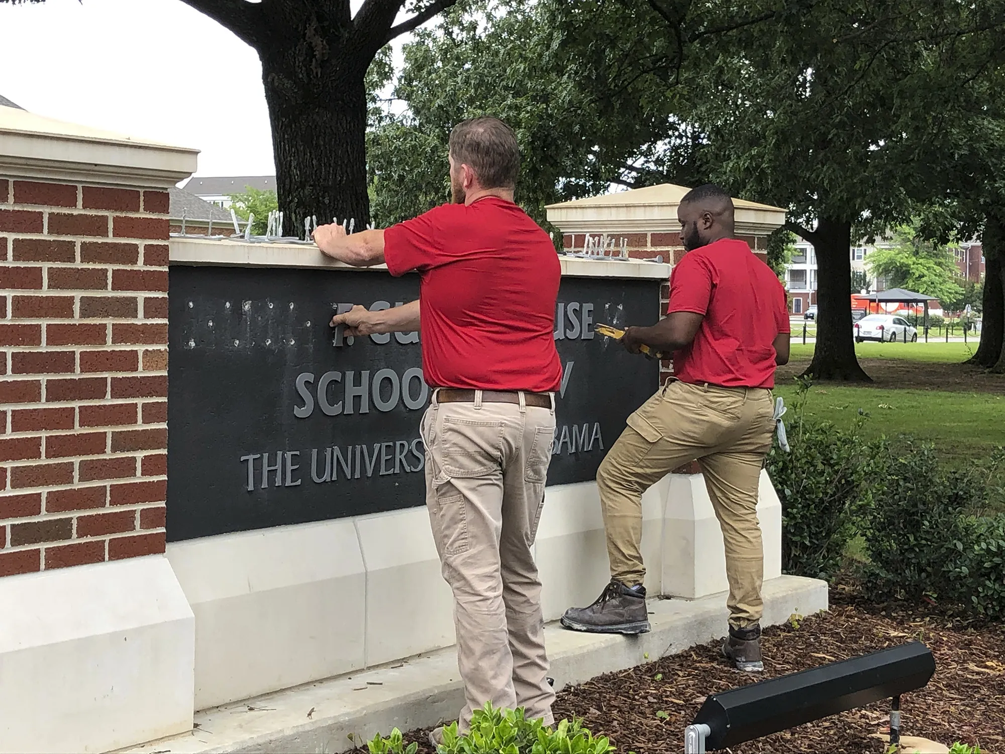 University of Alabama employees remove the name of Hugh F. Culverhouse Jr. off the School of Law sign in Tuscaloosa, Ala., Friday, June 7, 2019.