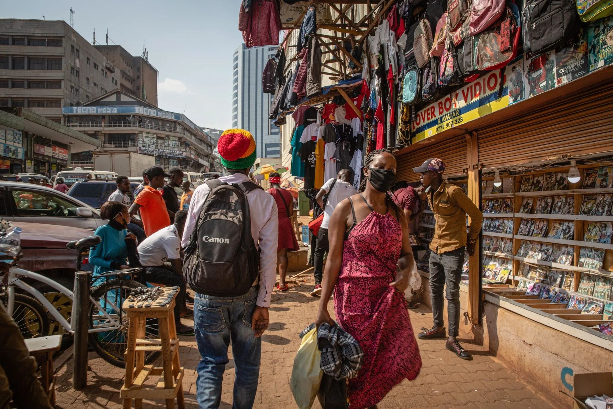 A pedestrian wearing a protective mask walks past market vendors in downtown Kampala, Uganda, on June 23, 2020.