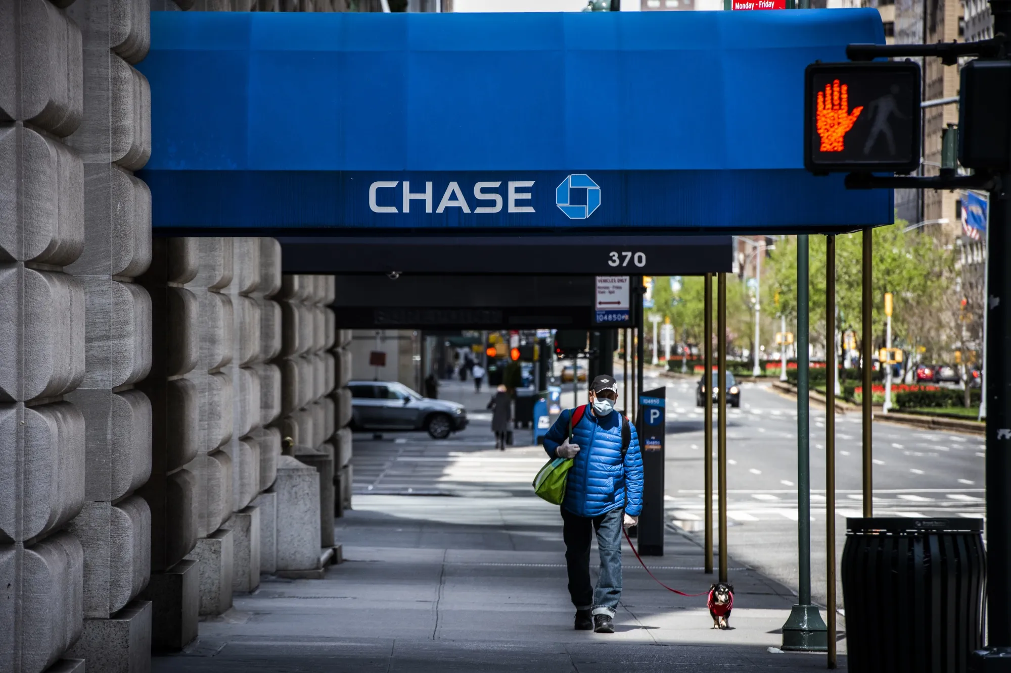 A pedestrian wearing a protective mask walks a dog past a temporarily closed JPMorgan Chase & Co. bank branch.