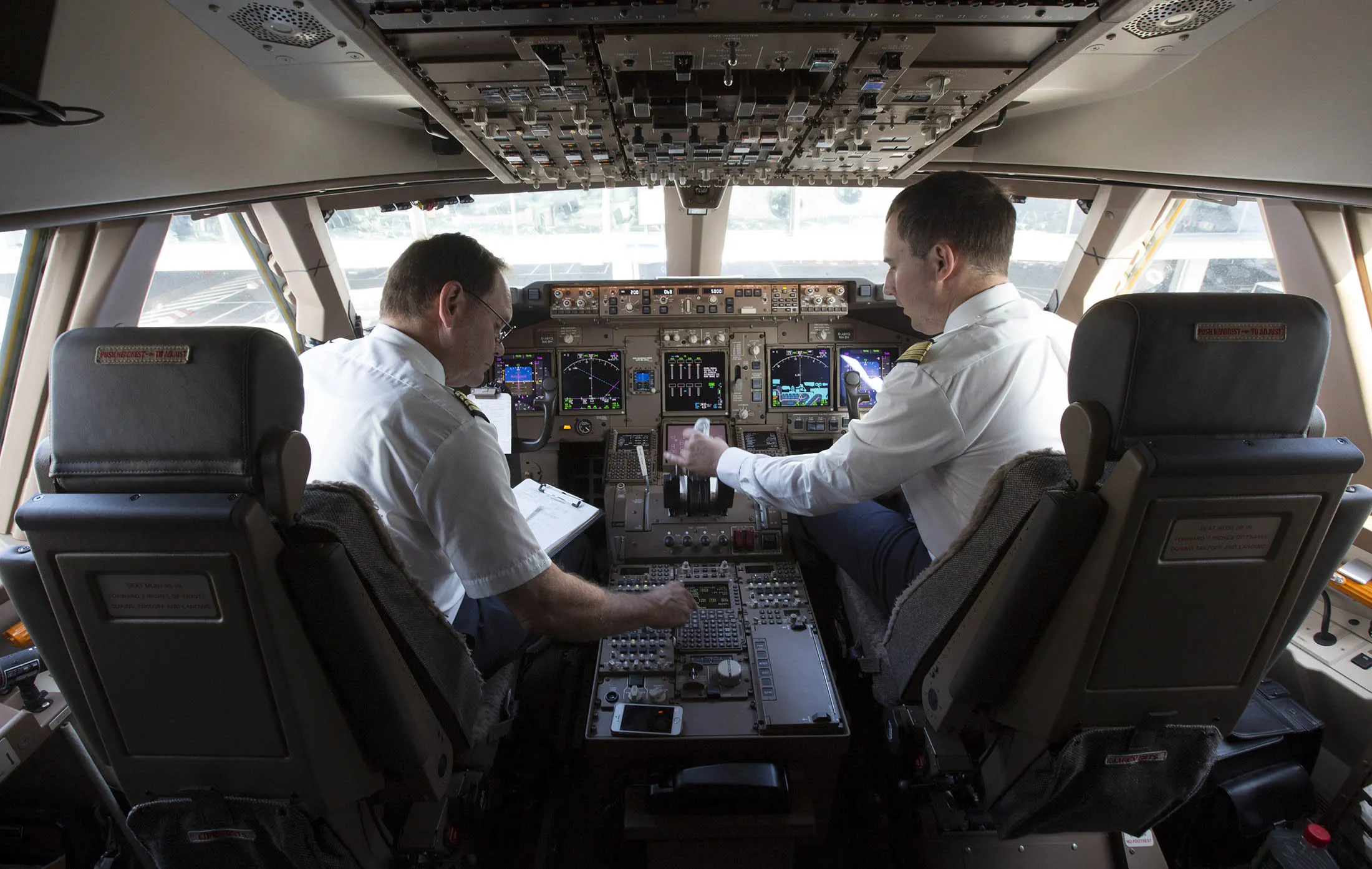 Pilots sit in the cockpit of a Boeing 747-8 passenger aircraft.
