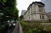 Pedestrians walk past the Bank of Japan (BOJ) headquarters in Tokyo, Japan, on Monday, July 8, 2019. Governor Haruhiko Kuroda said extremely low interest rates will be kept in place until at least around next spring while the bank will keep an eye on risks for price momentum.