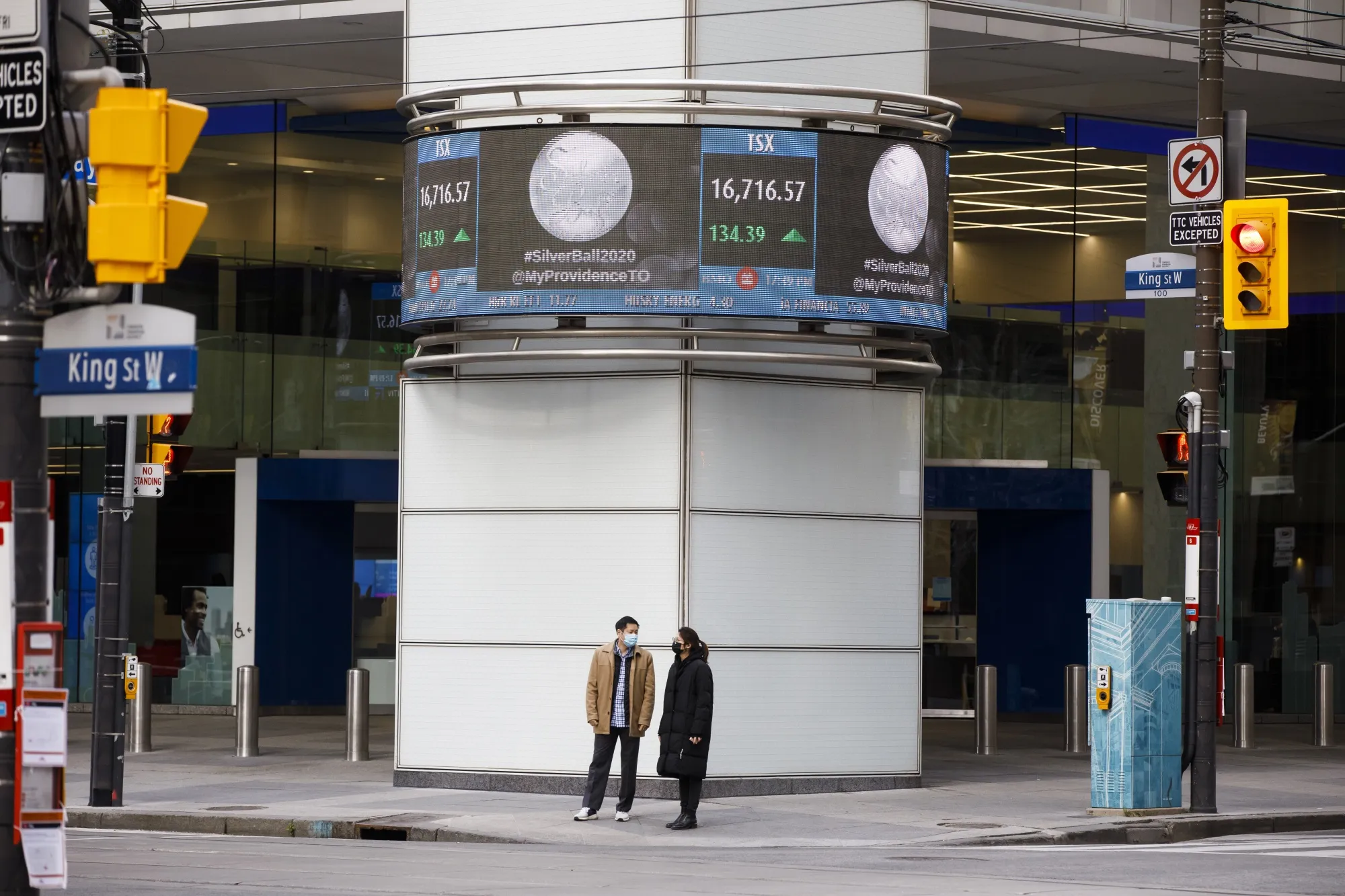 Pedestrians wearing protective masks pass by TSX ticker in Toronto on Nov. 13.