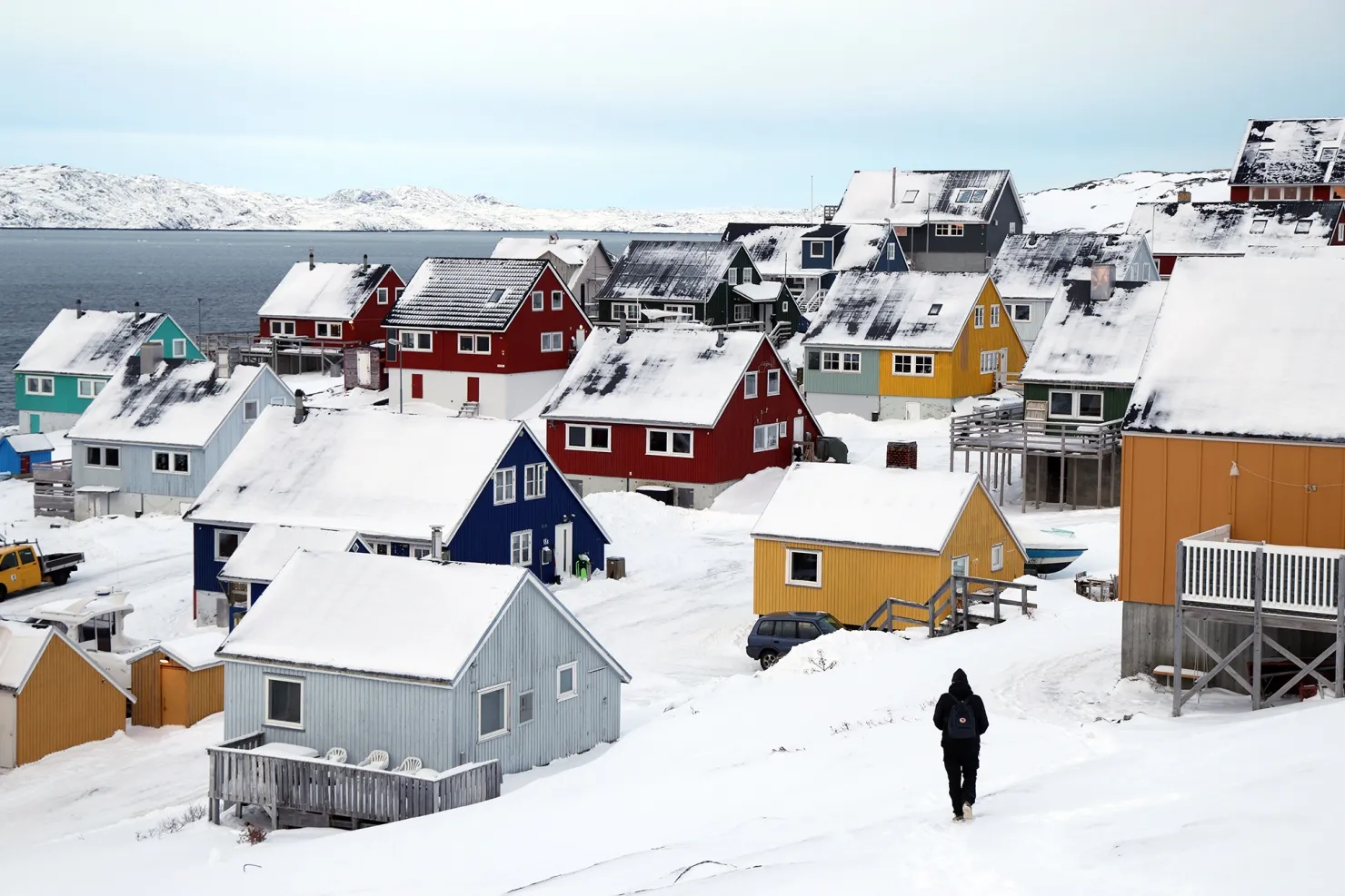 A man walks towards residential houses in Nuuk, Greenland.