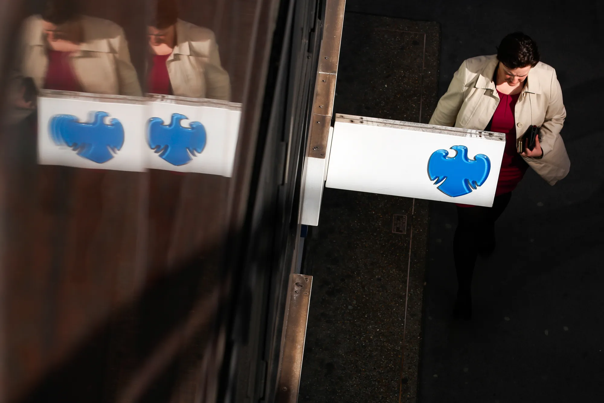 A pedestrian passes signage outside a Barclays Plc bank branch in London.
