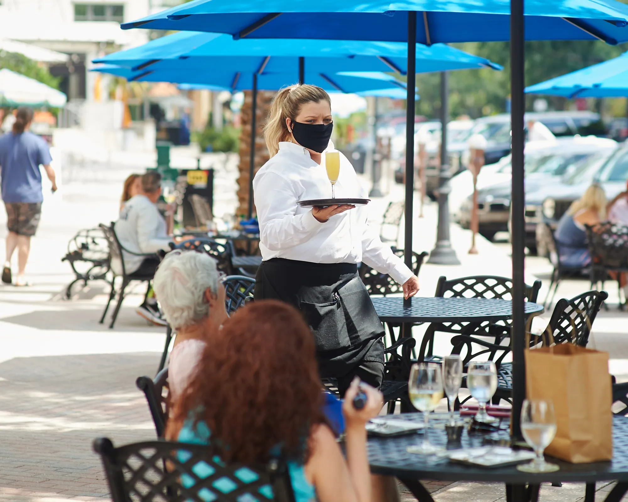 A server wearing a protective mask serves a drink to a customer in the outside dining area of a restaurant in St. Petersburg, Florida, on&nbsp;May 4.