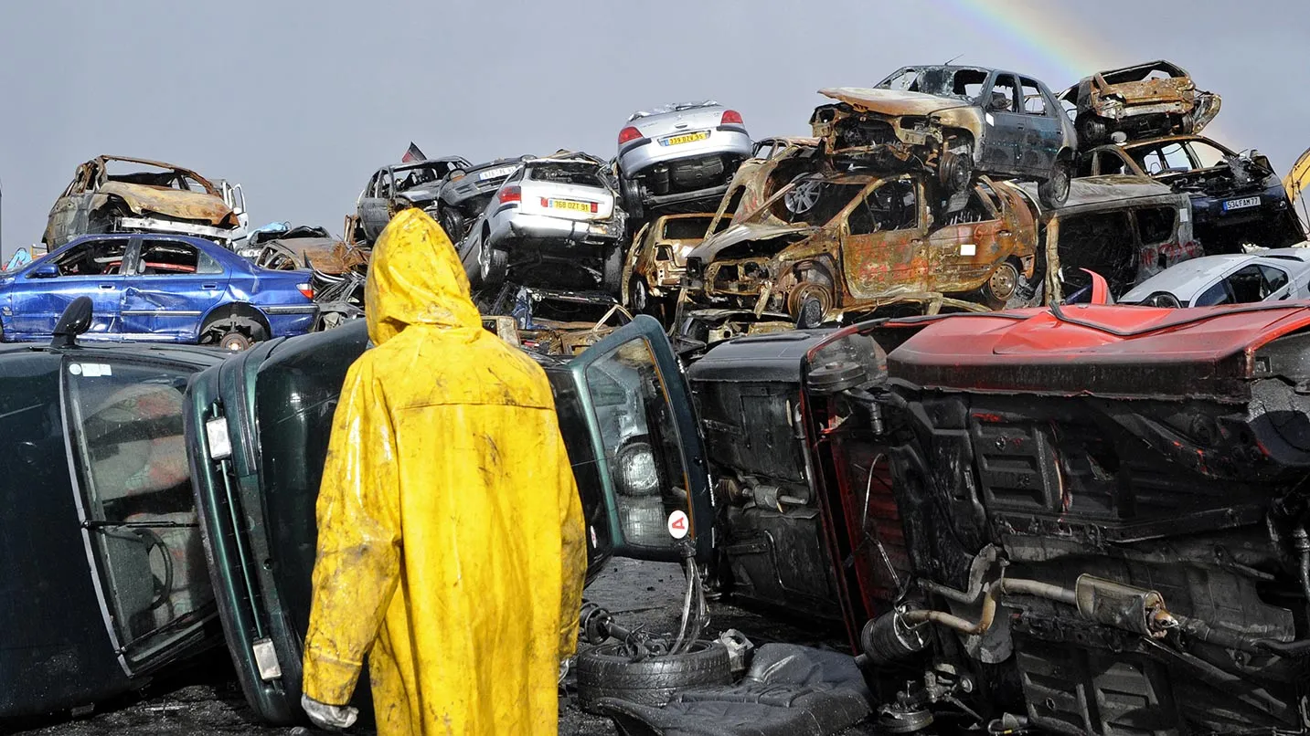 An employee passes a pile of damaged cars at a car demolition site in Athis Mons, France.
