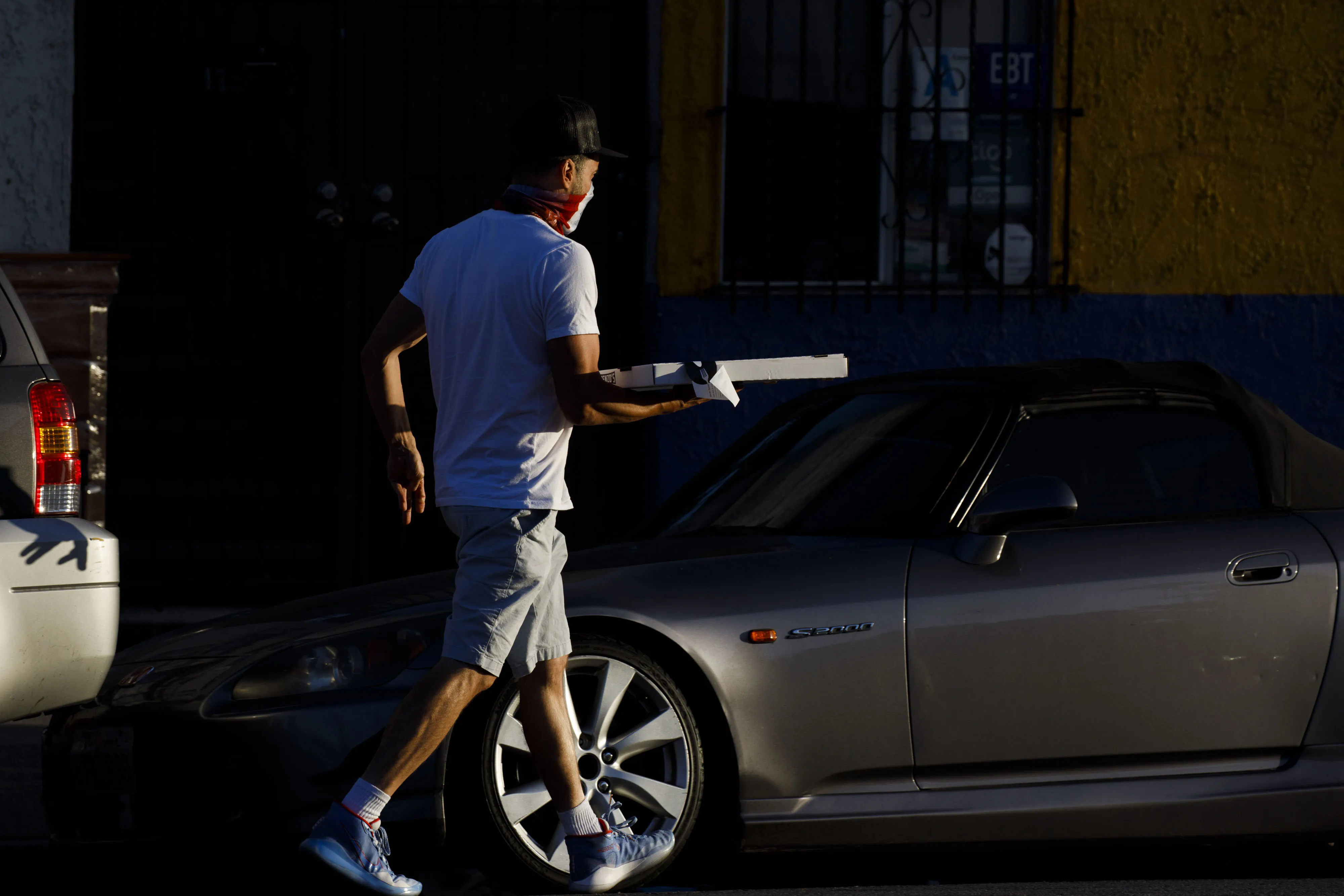 A food delivery driver picks up a pizza from a restaurant in Los Angeles.