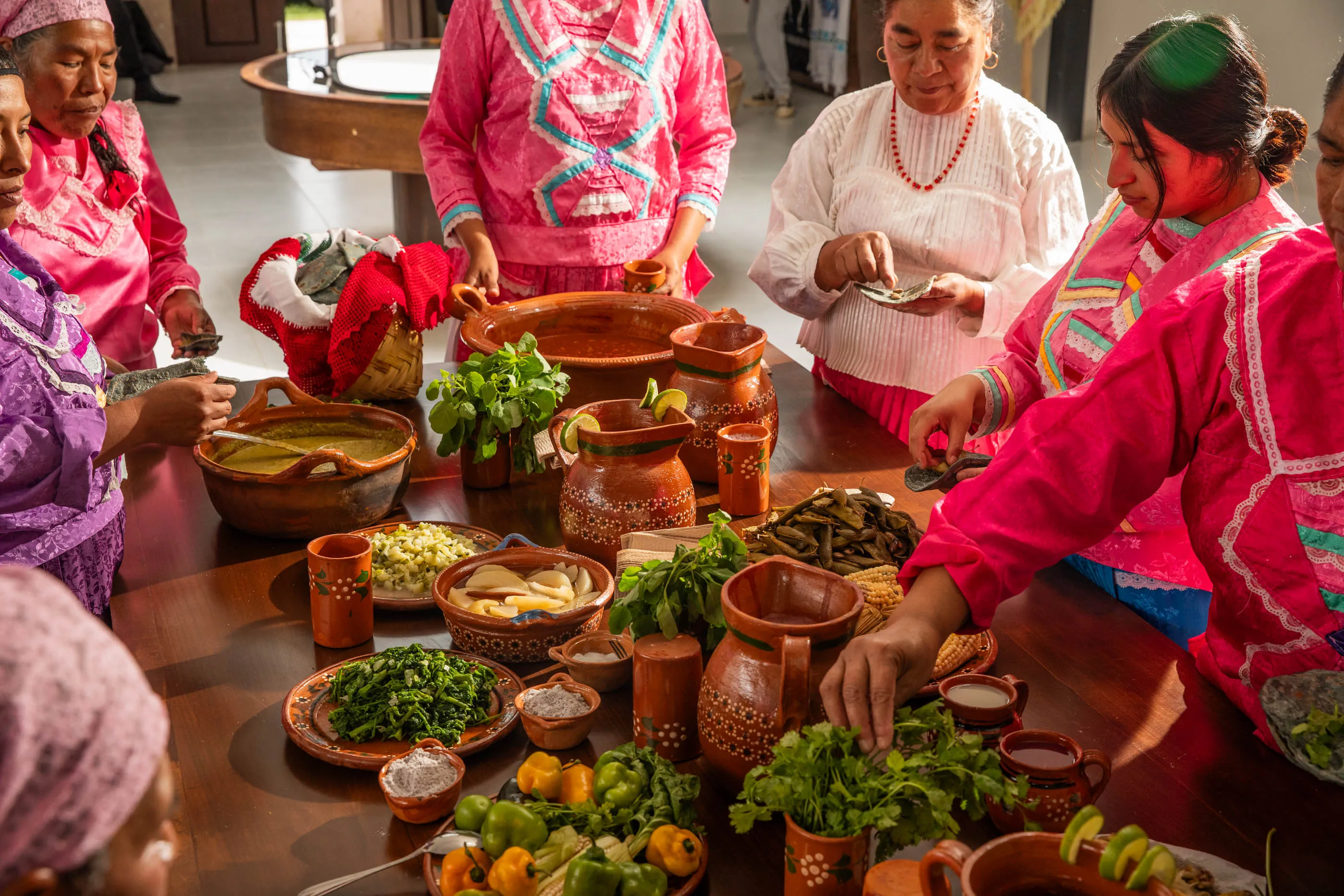A group of Mazahua women in traditional pink dresses prepare an elaborate meal at the Casa de la Cultura in Crescencio Morales.