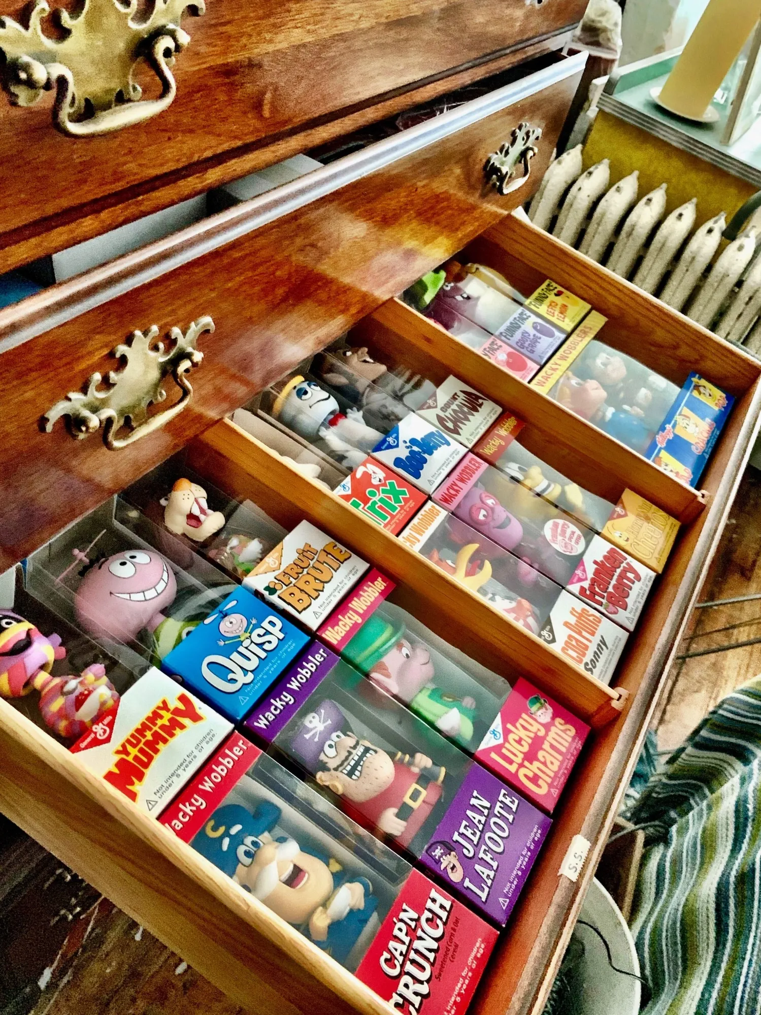 A collection of cartoon bobbleheads, including Cap’N Crunch and the Lucky Charms leprechaun, in a dresser drawer in Nick Malis’s mother’s apartment.
