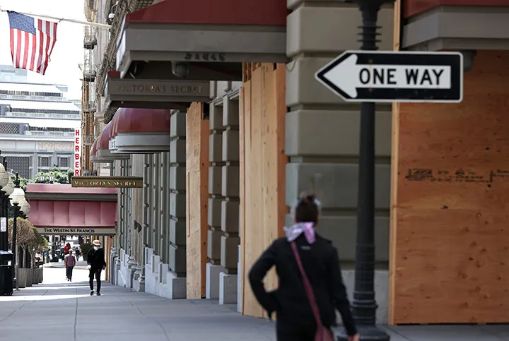 Pedestrians walk by boarded up businesses in San Francisco, California.&nbsp;